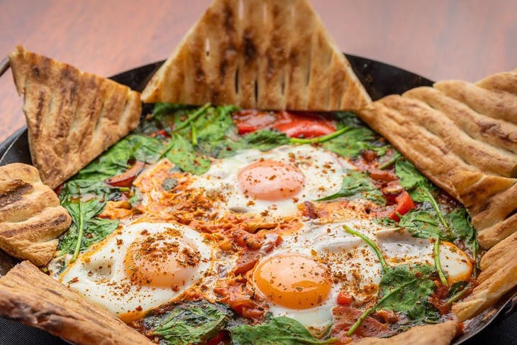A plate of shakshuka served with triangles of toast for dipping.
